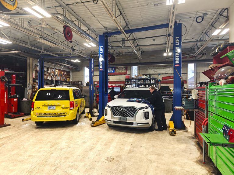 Two vehicles raised on lifts inside the service bays, tool cabinets lining the wall