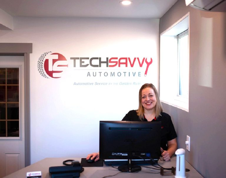 Tech Savvy Automotive front desk in Brantford, staff member at the counter below the shop's wall logo