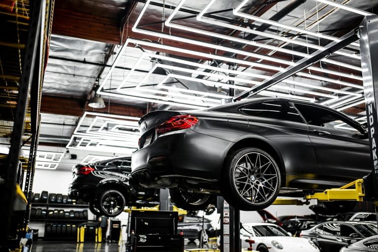 Black sedan raised on a lift in a service bay