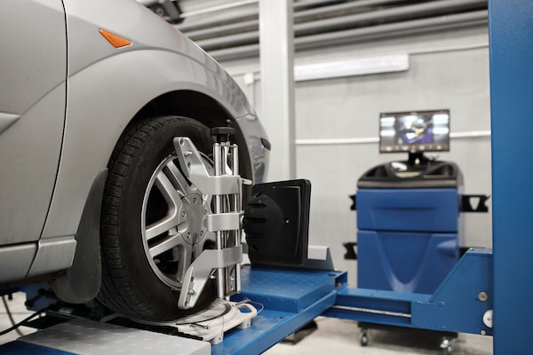 Car on an alignment rack with sensor targets and a monitor behind