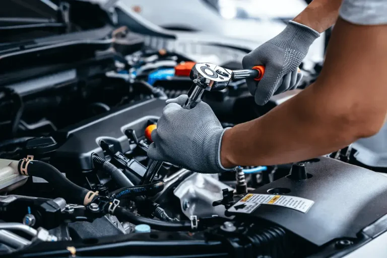 Gloved hand using a ratchet in an engine bay