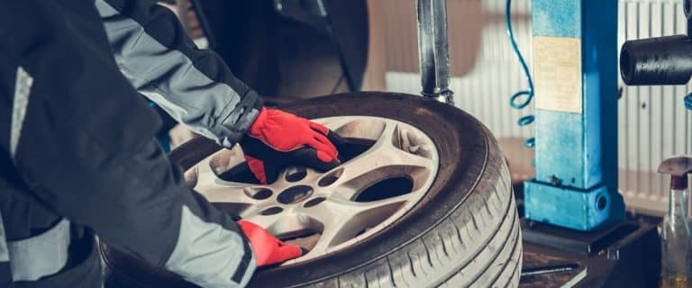 Hands in red gloves removing a wheel with an impact wrench