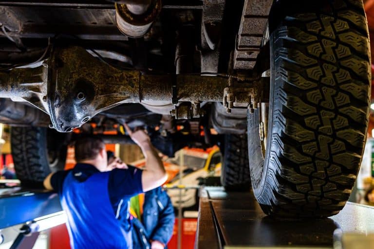 Mechanic inspecting the undercarriage of a lifted truck