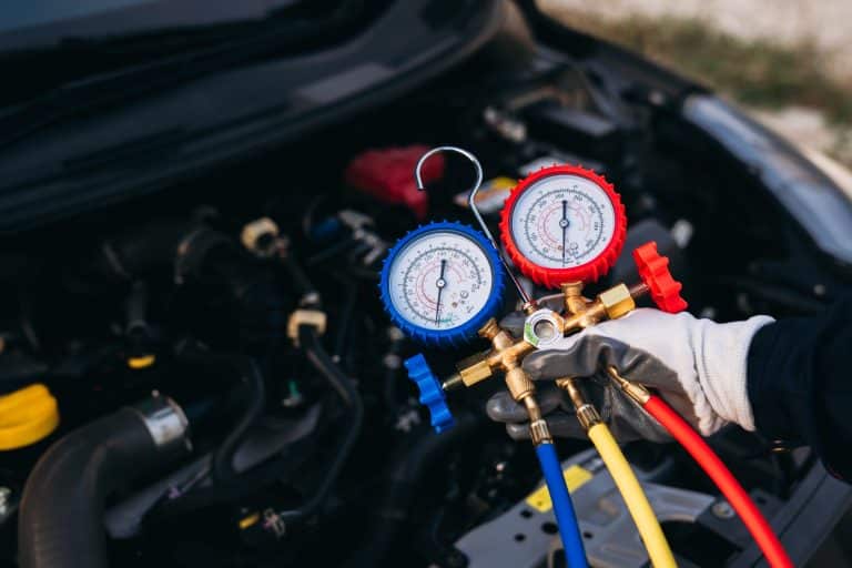 Close-up of a gloved hand holding an AC manifold gauge set