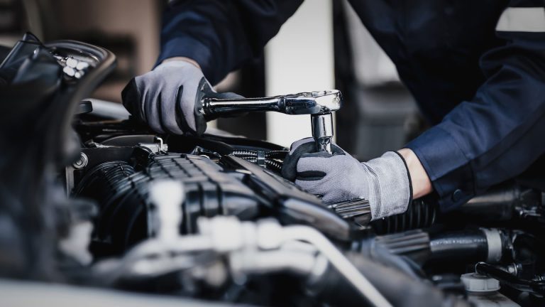 Gloved hands using a ratchet wrench on engine components