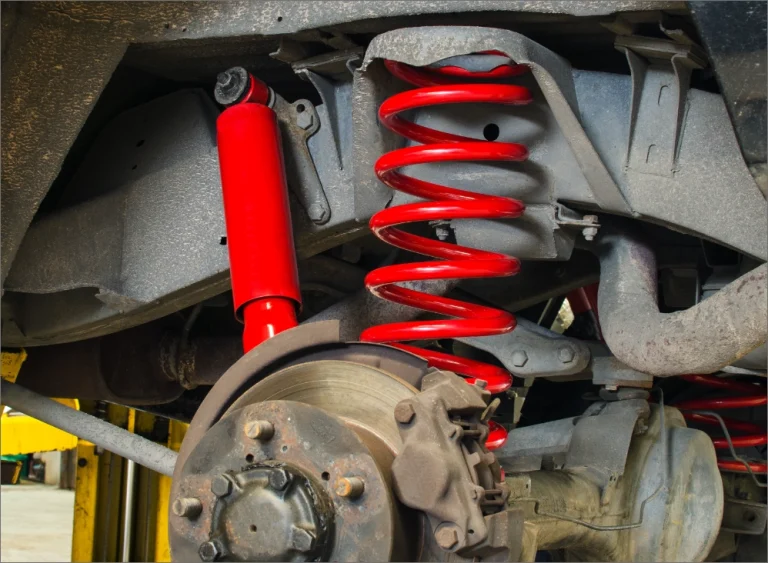 Red shock absorber and coil spring beside a brake assembly