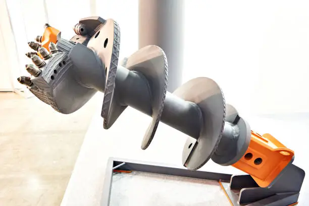 Auger drill bit with an orange fitting on a white background