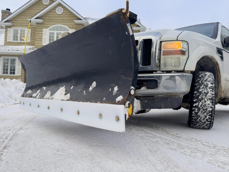 Close-up of a snow plow blade mounted on the front of a pickup truck