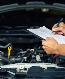 Red-sleeved hand writing on a checklist over an engine bay