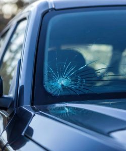 Spiderweb crack across the windshield of a dark sedan