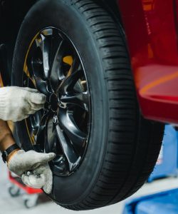 Gloved hands fitting an alloy wheel with an impact wrench