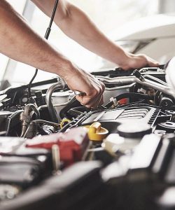 Mechanic reaching into an engine bay to work on engine components