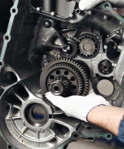 Gloved hands working on a transmission gear housing