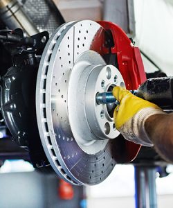 Gloved hands using a wrench on a brake disc
