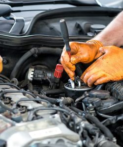 Gloved hands working near the oil filter in an engine bay
