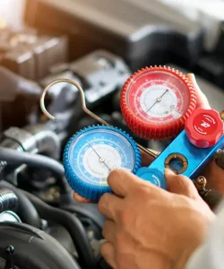 Hand holding an AC gauge hose in an engine bay