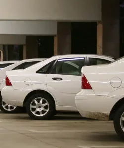 Row of white fleet sedans parked beside a building
