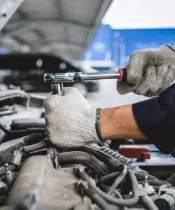 Gloved hands using a socket wrench in an engine bay